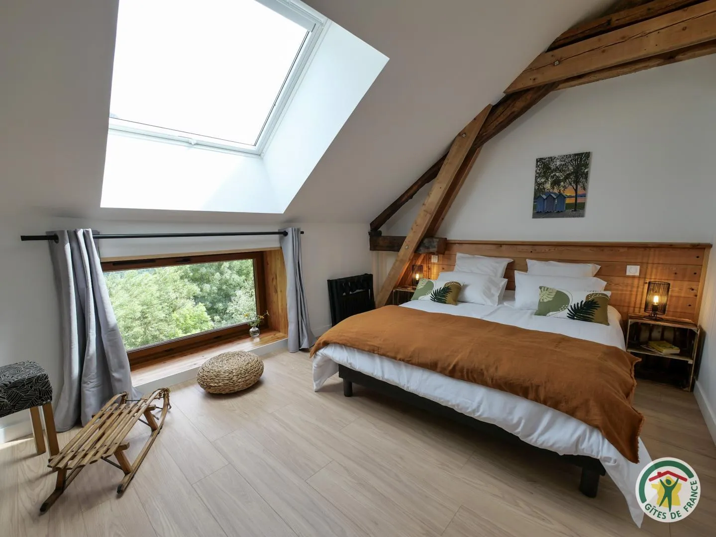 Le lit double de Pic Saint André sous la charpente apparente, face à la fenêtre ouverte sur les arbres