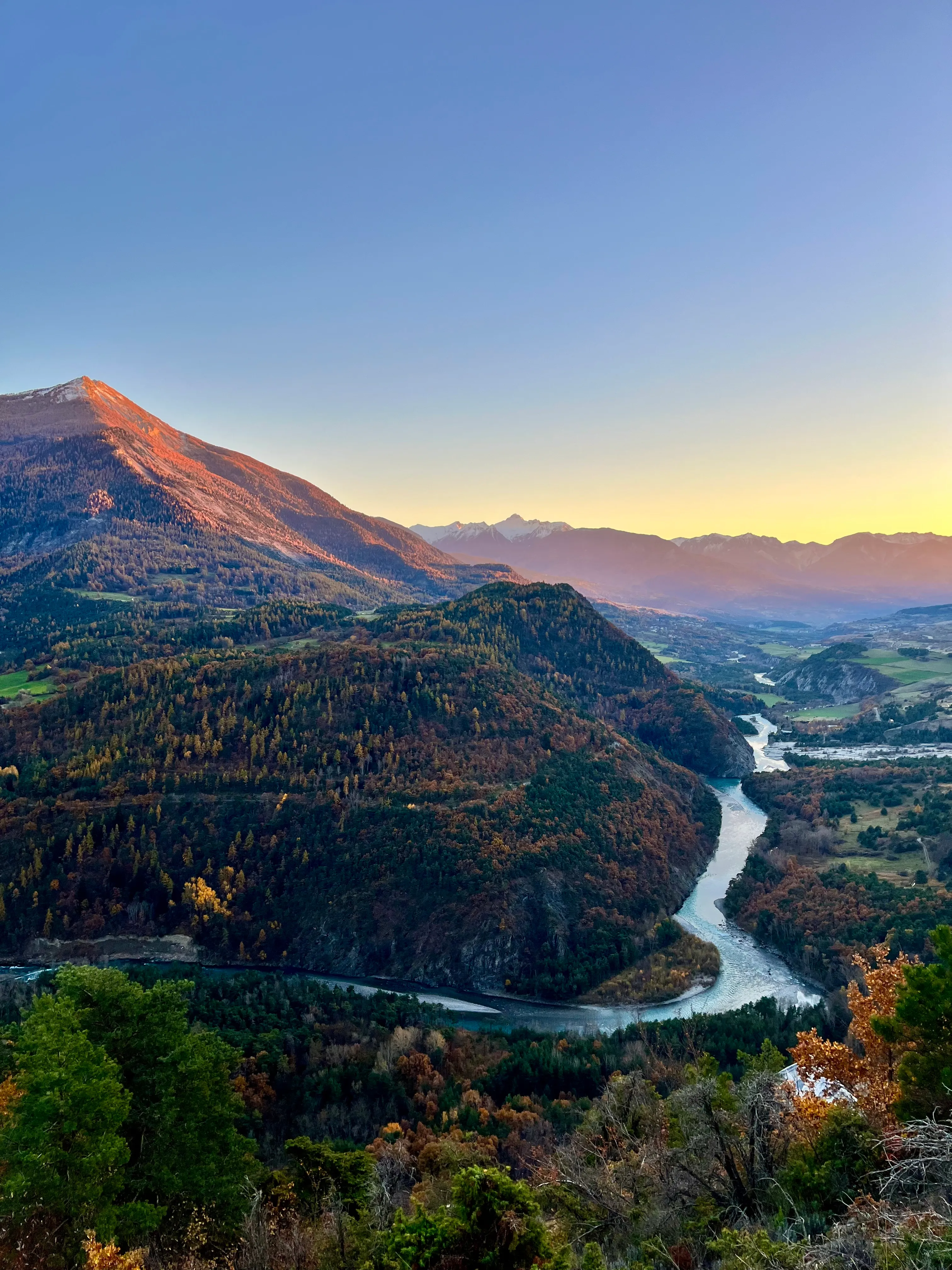 La Durance serpentant dans la vallée au coucher du soleil, les derniers rayons éclairant le flanc de la montagne